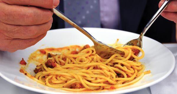 Closeup of a senior twirling his fork in a plate of spaghetti