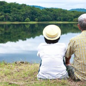Photo of an elder couple sitting and looking out at a lake