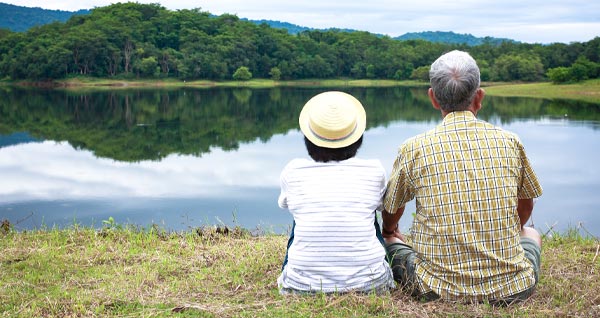 Photo of an elder couple sitting and looking out at a lake