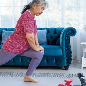 photo of elder woman doing exercises in front of her couch